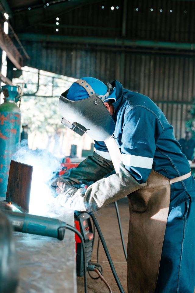Welder in a helmet working on a steel plate