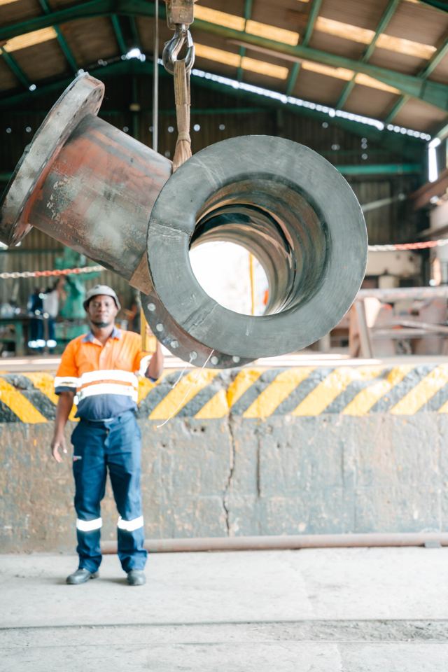 Worker standing beside a large rubber-lined pipe elbow
