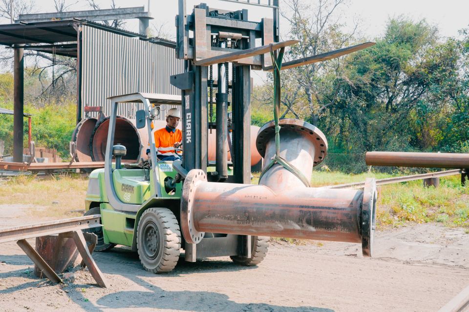 Forklift moving a lined pipe fitting on site